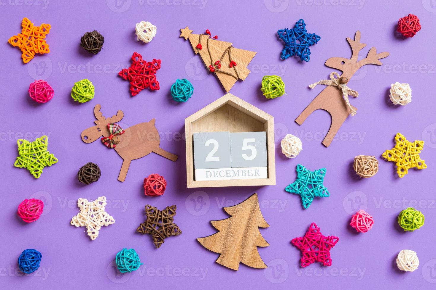 Top view of wooden calendar. The twenty fifth of December. New Year decorations on purple background. Festive stars and balls. Merry Christmas concept photo