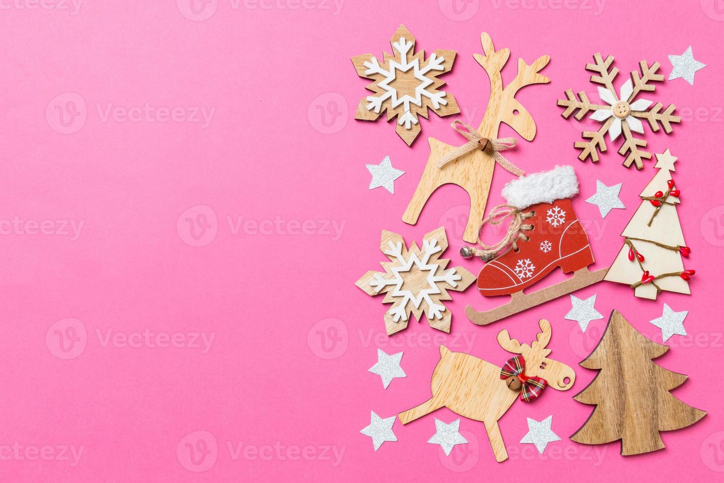 Top view of pink background decorated with festive toys and Christmas symbols reindeers and New Year trees. Holiday concept with copy space photo