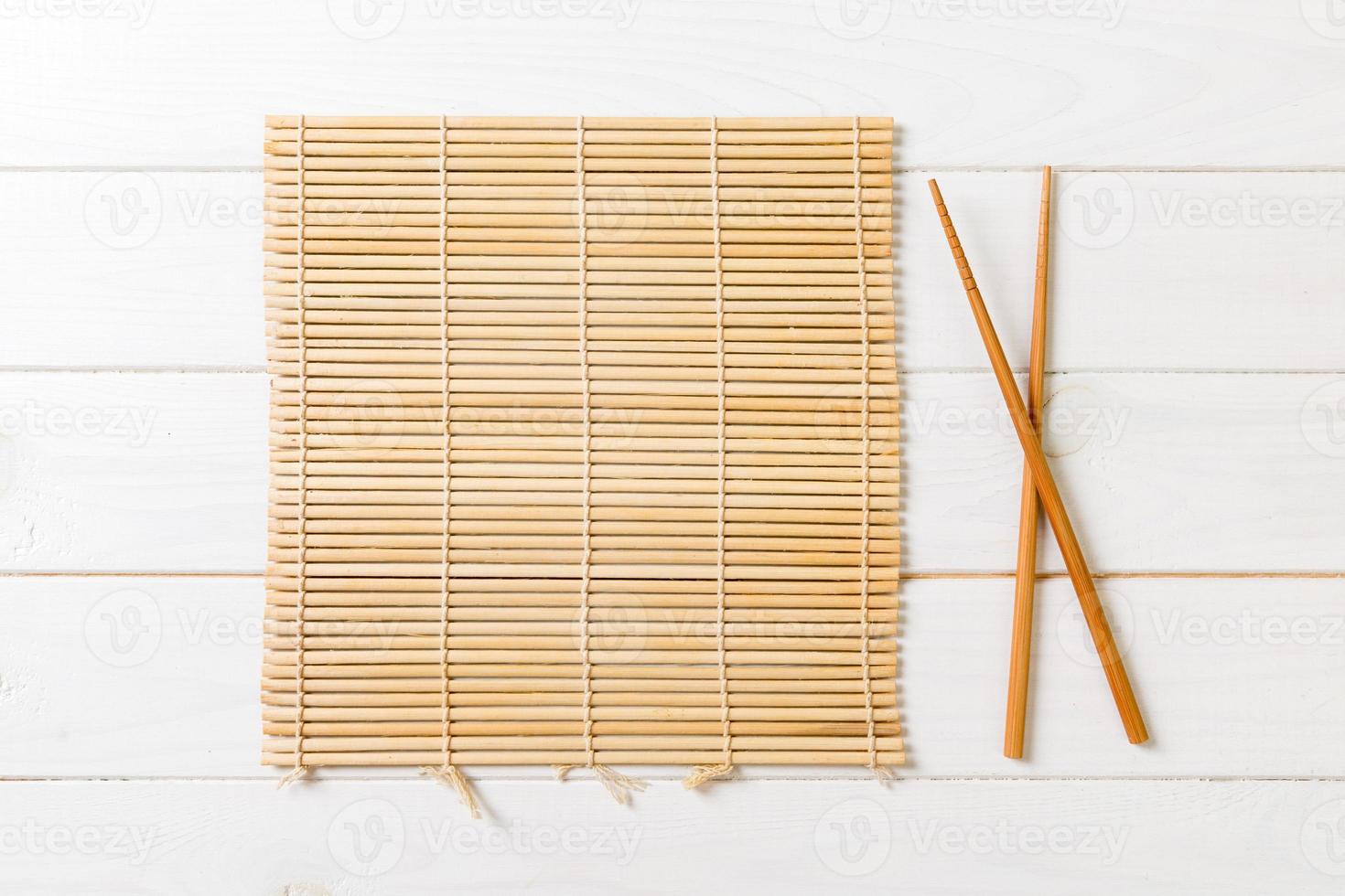 two sushi chopsticks with empty bamboo mat or wood plate on wooden Background Top view with copy stace photo
