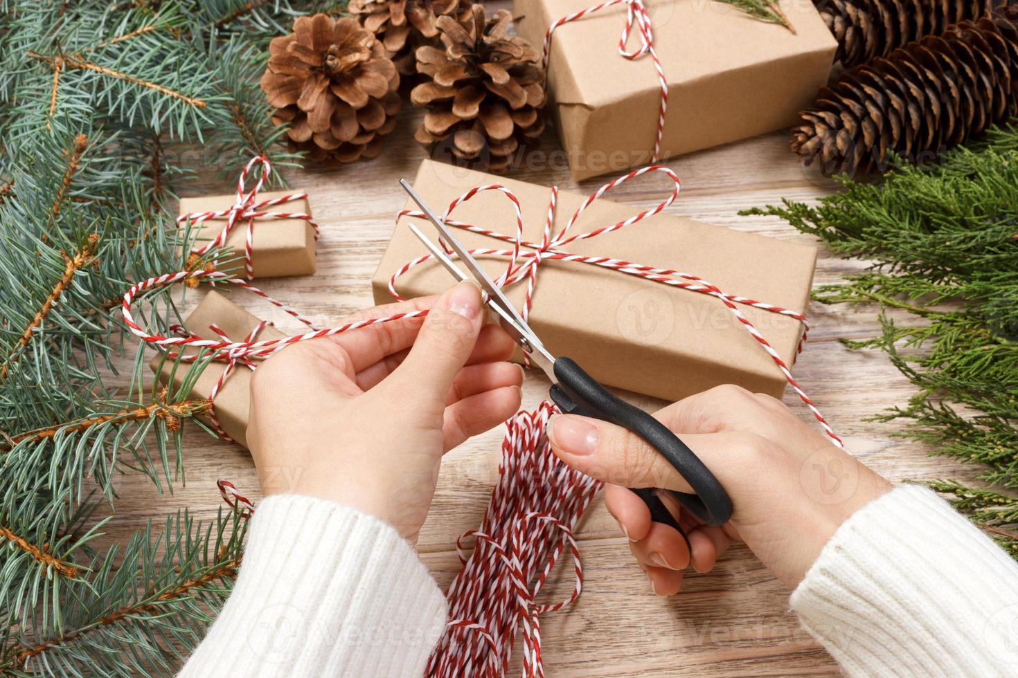 Hands wrapping a gift over wooden table. Directly above. Christmas time photo