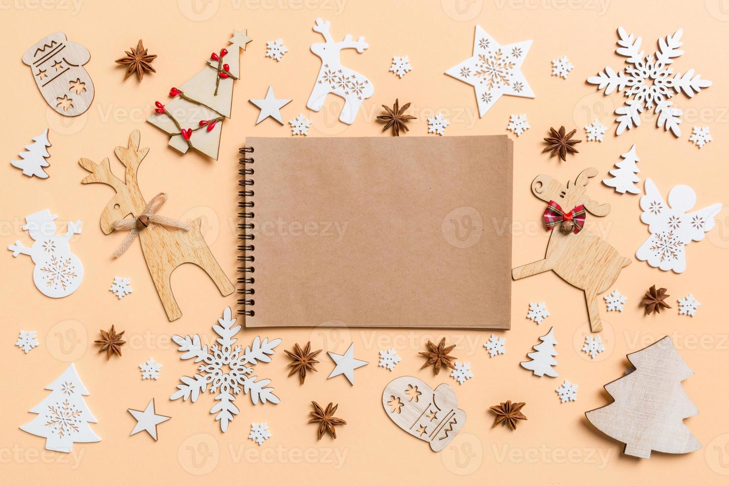 Festive decorations and toys on orange background. Top view of notebook. Merry Christmas concept photo