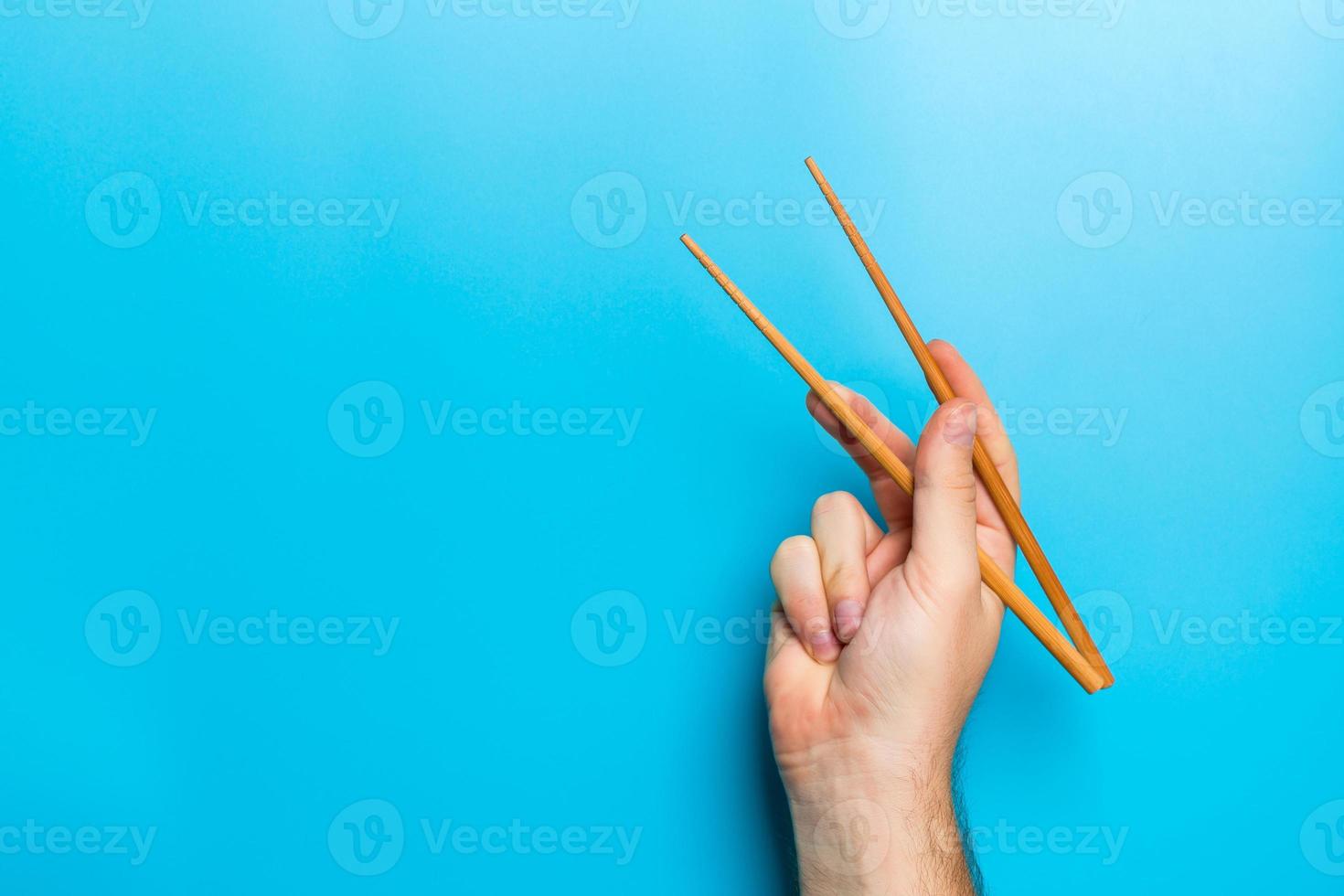 Wooden chopsticks in male hand on black background with empty space for your idea. Tasty food concept photo