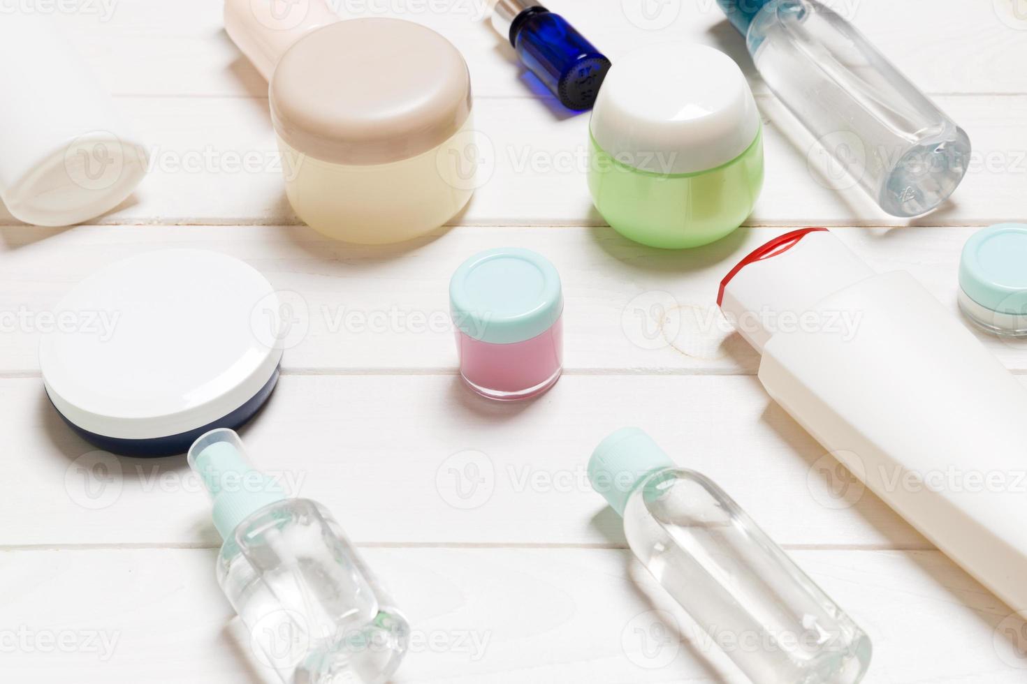Close-up view of cosmetic bottles, jars, containers and sprays on white wooden background. Beauty concept with copy space photo