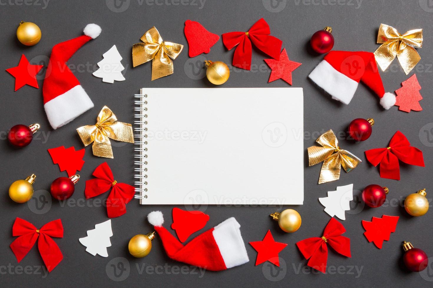 Top view of notebook on black background with New Year toys and decorations. Christmas time concept photo