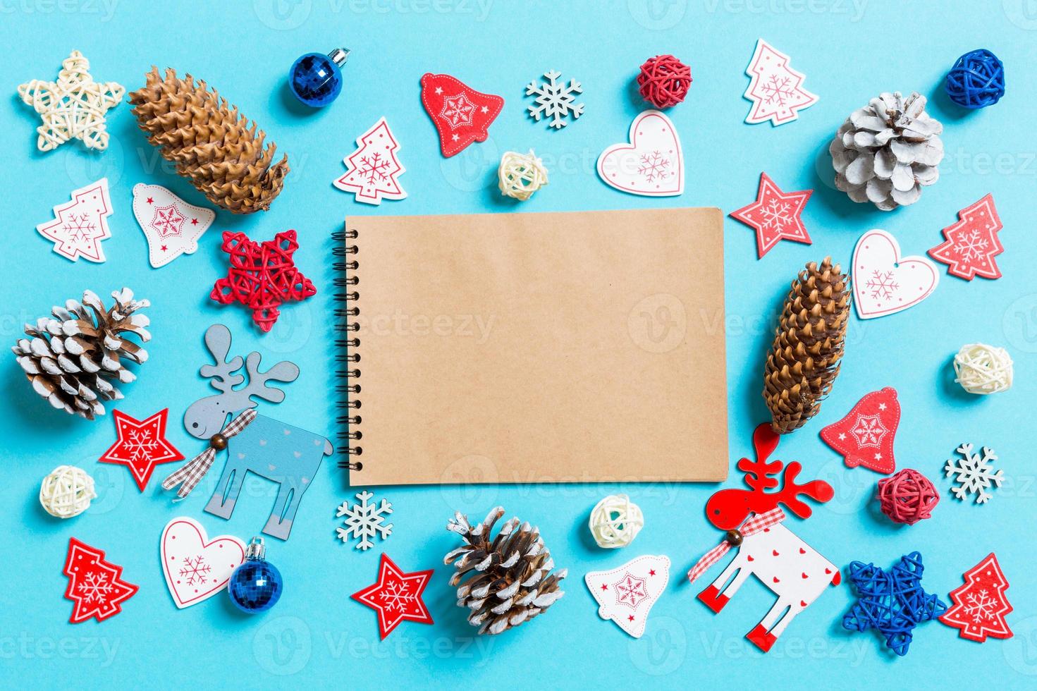 Top view of notebook surrounded with New Year toys and decorations on blue background. Christmas time concept photo