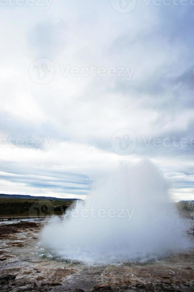 The Great Geysir, geyser in southwestern Iceland, Haukadalur valley. Geyser splashing out of the ground against the background of a cloudy sky photo