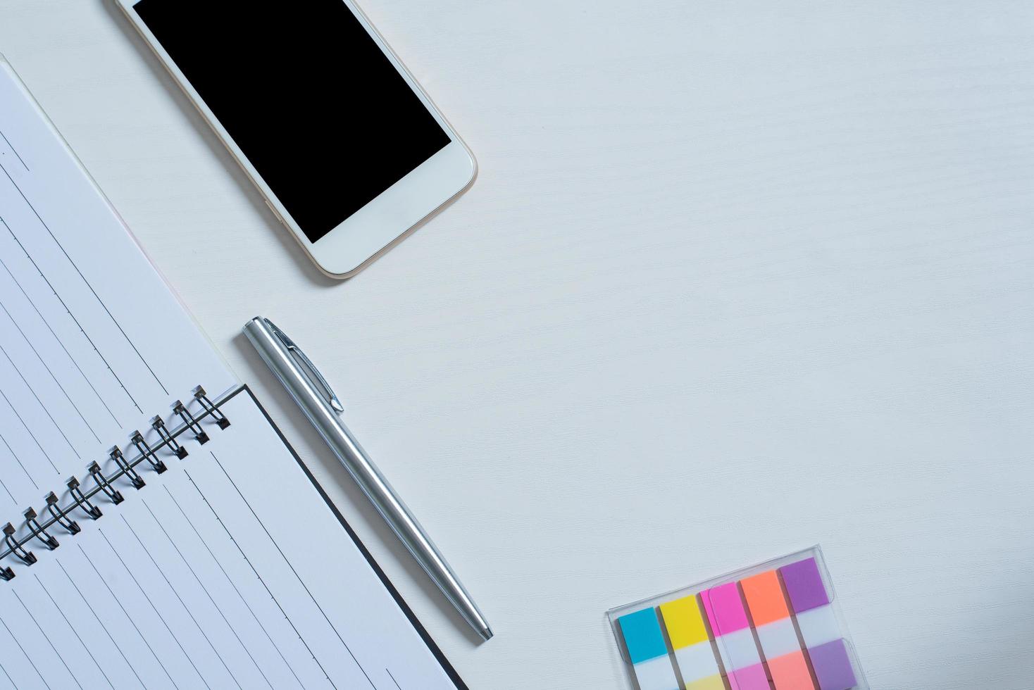 Top view of Cellphone ,  Open book, pen, mini colorful paper note photo