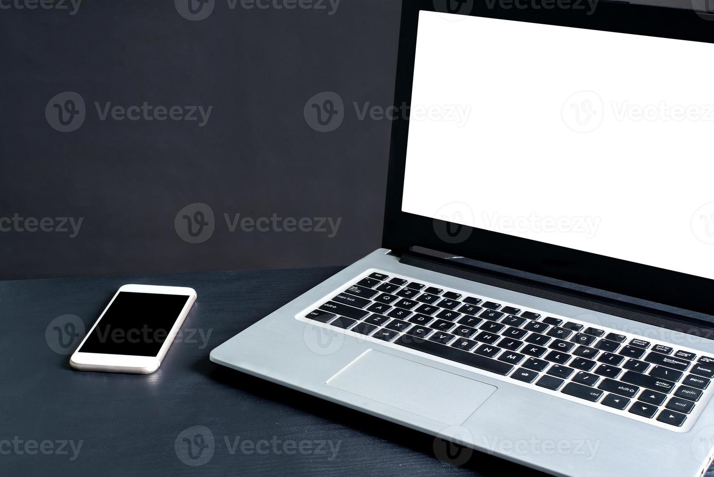 Laptop, smartphone, on black wooden table with black background photo