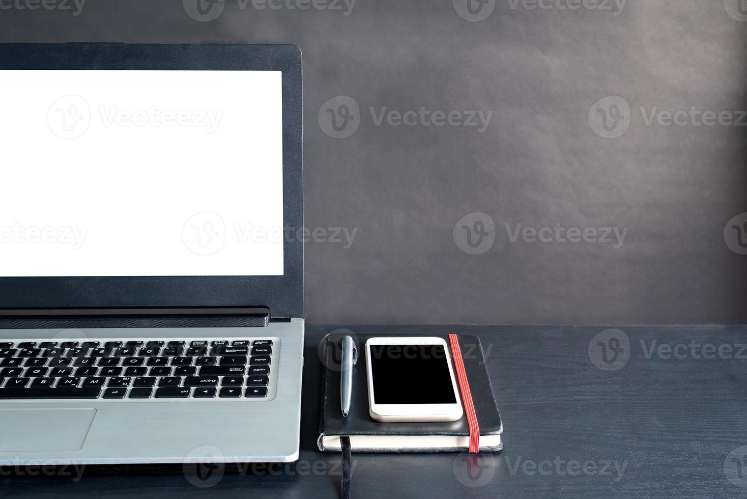 Laptop, smartphone, notebook, pen, on black wooden table with black background photo