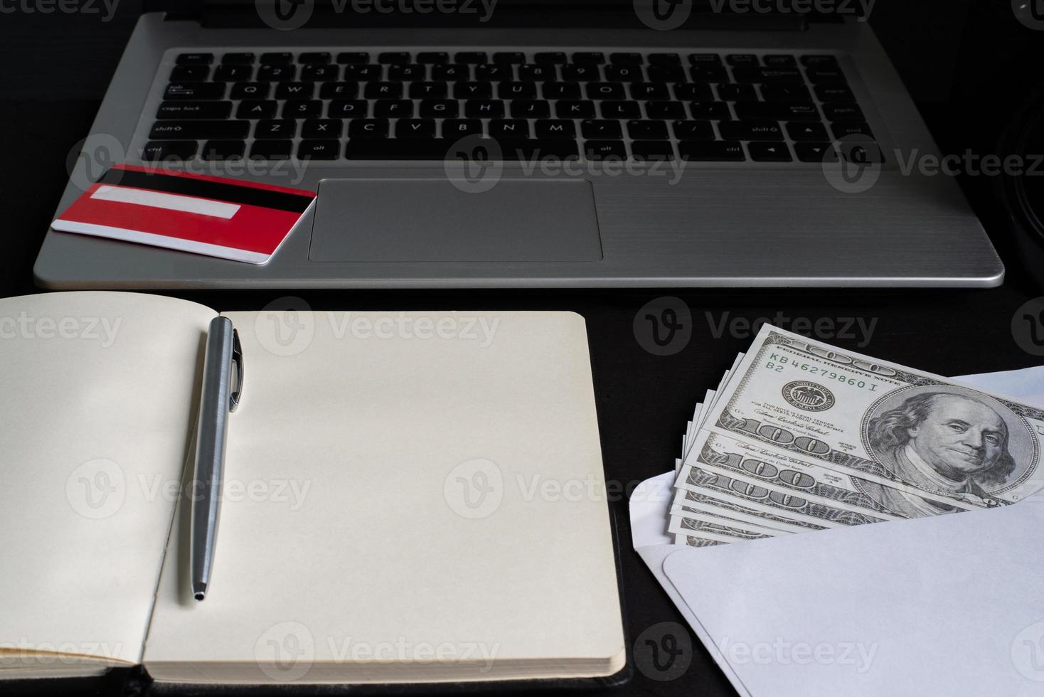 un cuaderno abierto con laptop, tarjeta de crédito, bolígrafo, dólares foto