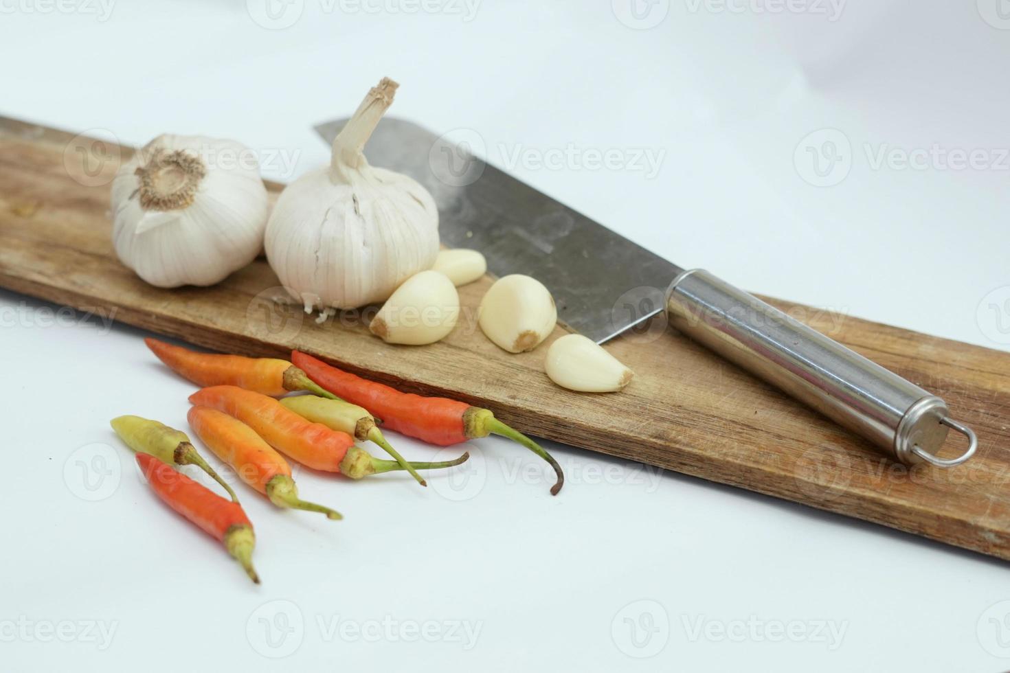 assorted spices, shallots, garlic and chilies on a cutting board and sharp knife photo