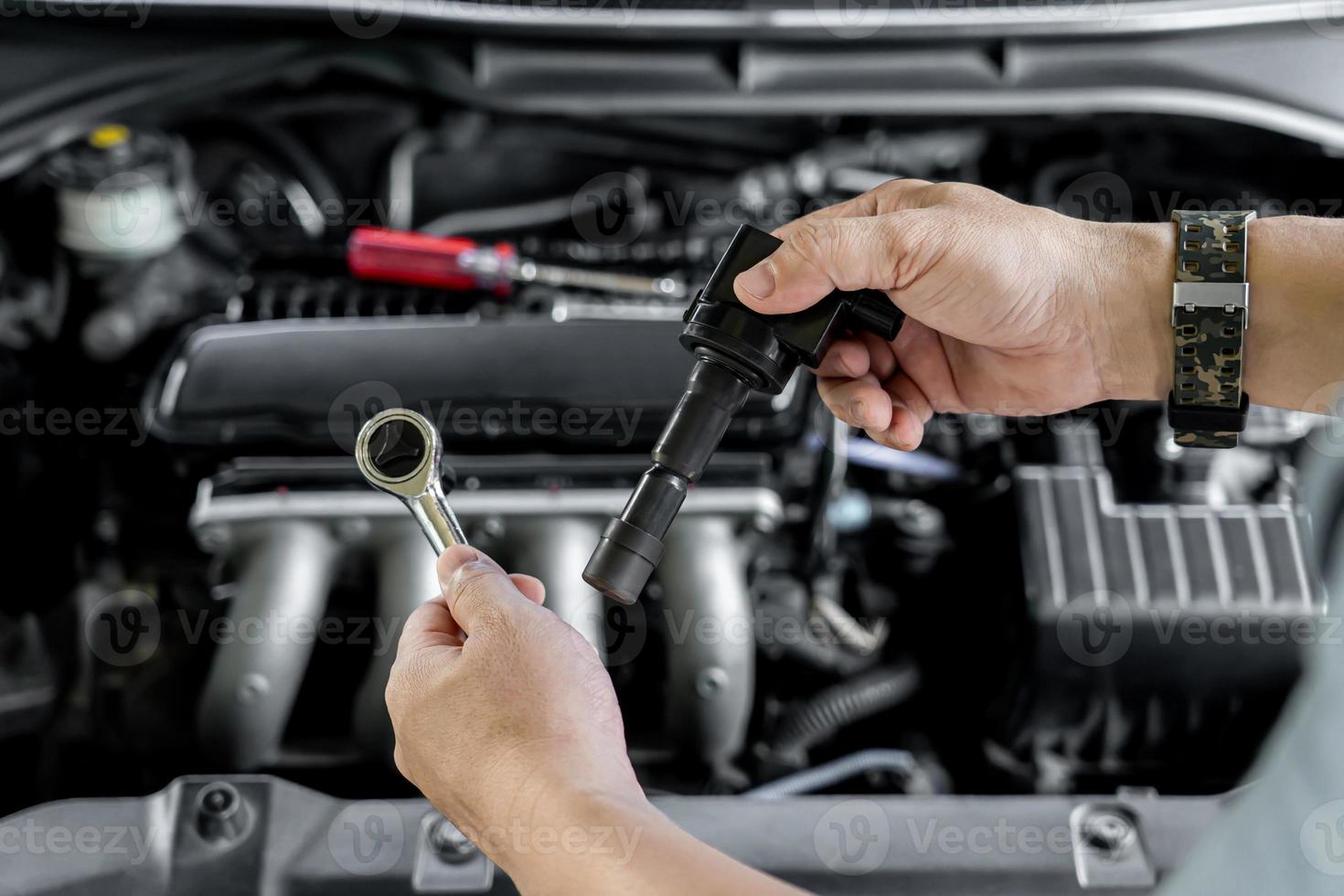 Close up spark plug coil in hand a man and use block wrench remove a bolt in service in garage and engine room  background photo