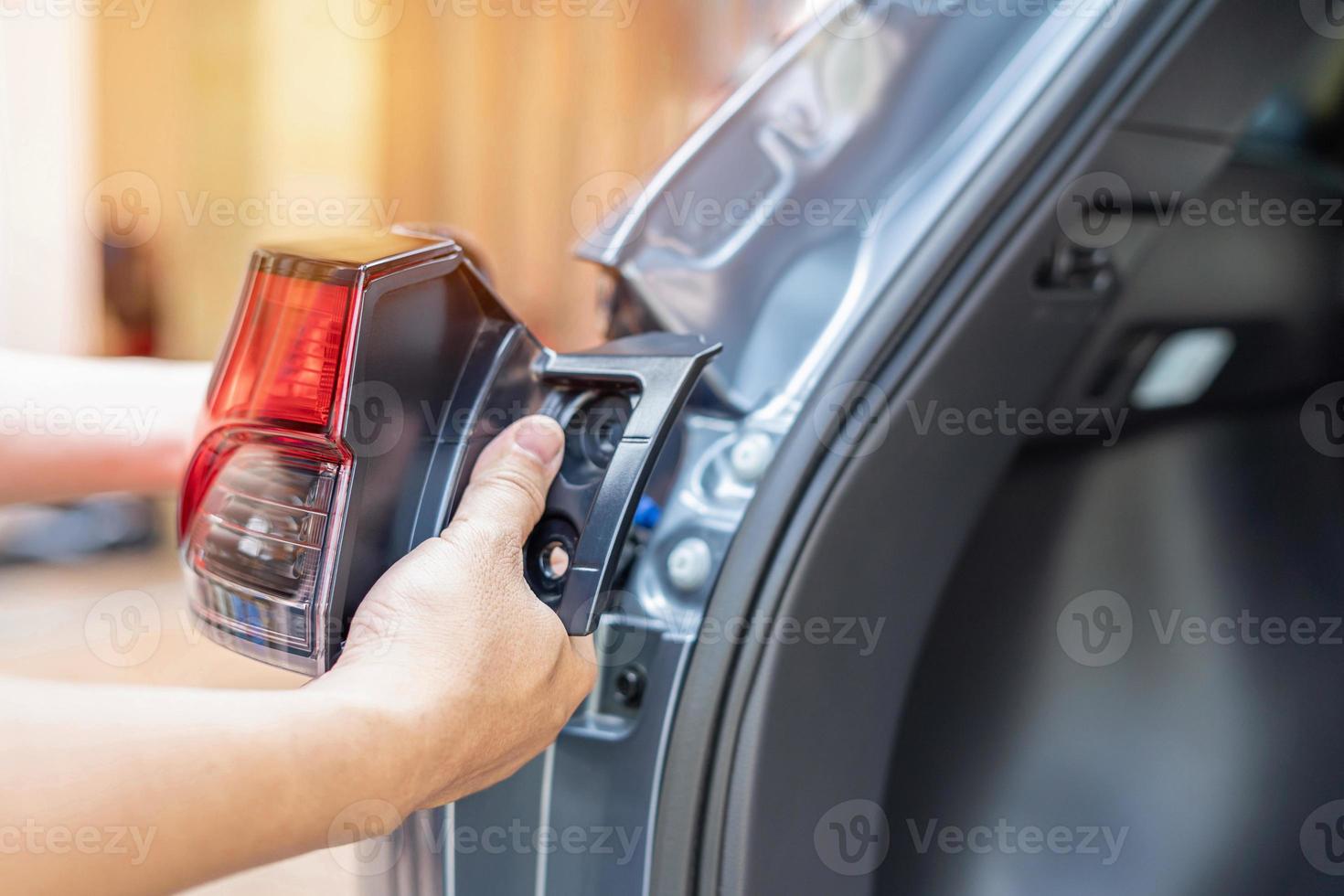 Close up hand a man holding car tail lights are being assembled with the car body Maintenance of lighting systems for safety concept photo