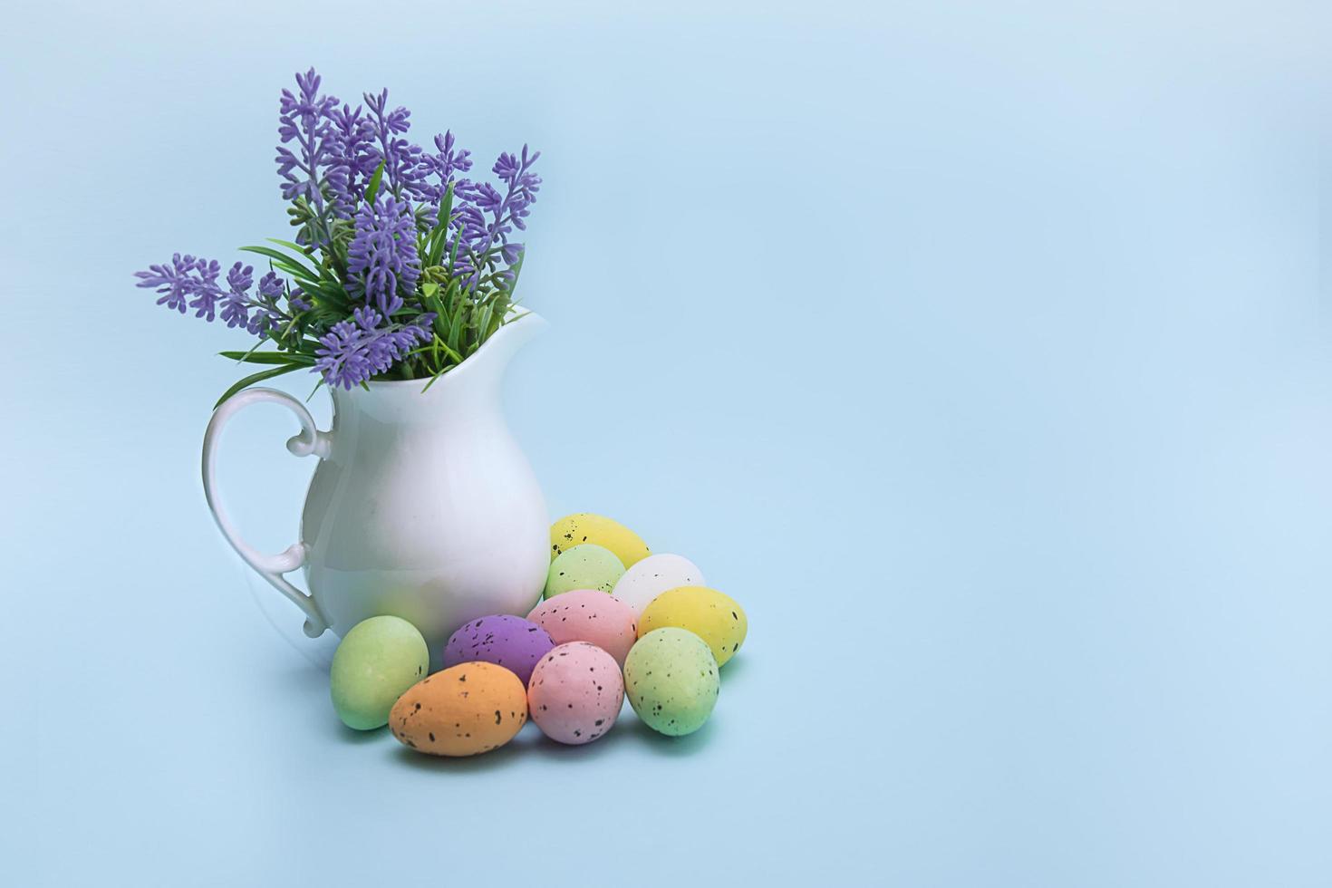 Easter colorful eggs on a blue background with spring flowers in a vase, Easter greeting card with space for text photo