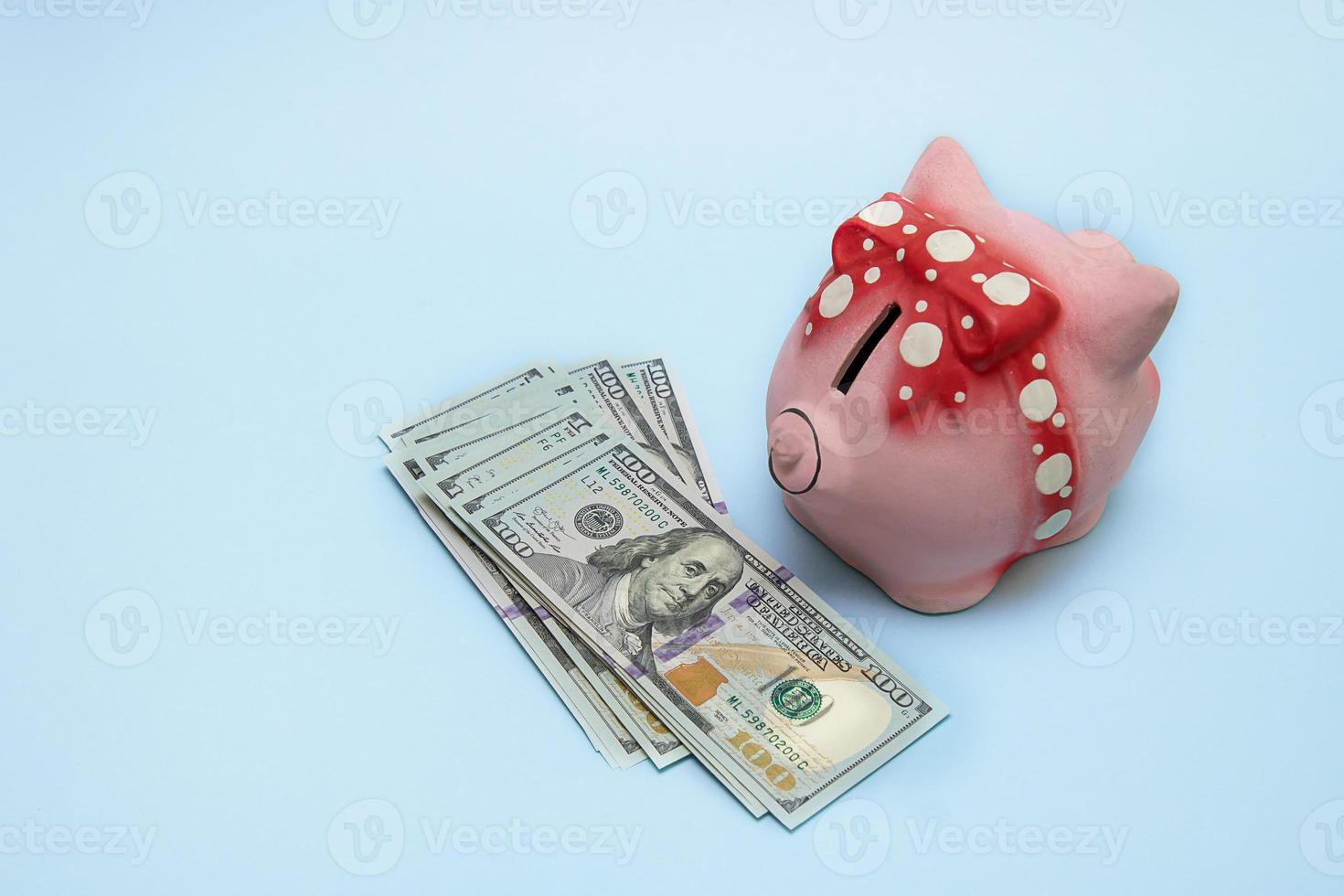 Money on a blue background, next to a piggy bank, the concept of accumulation, savings, finance photo