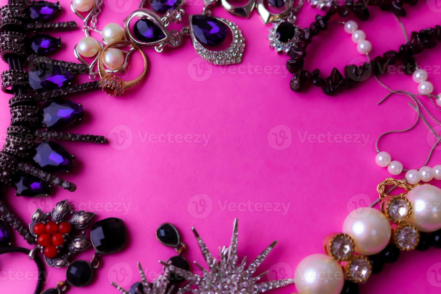 Beautiful precious shiny jewelery trendy glamorous jewelry set, necklace, earrings, rings, chains, brooches with pearls and diamonds on a pink purple background. Flat lay, top view, copy place photo