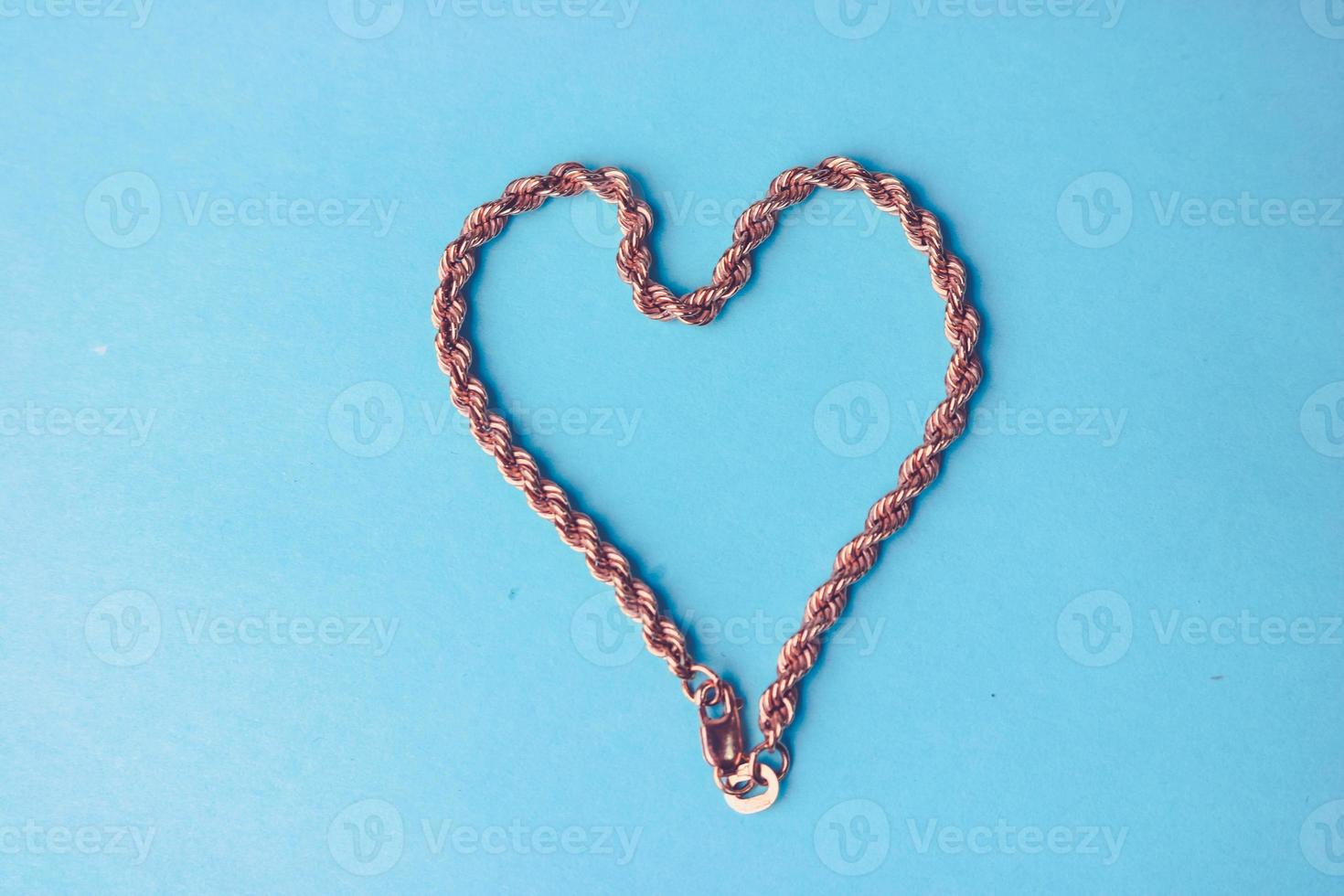 textura de una hermosa cadena dorada querida festiva de tejido único en forma de corazón sobre un fondo azul y espacio de copia. concepto amor, propuesta de matrimonio, matrimonio, st. día de San Valentín foto