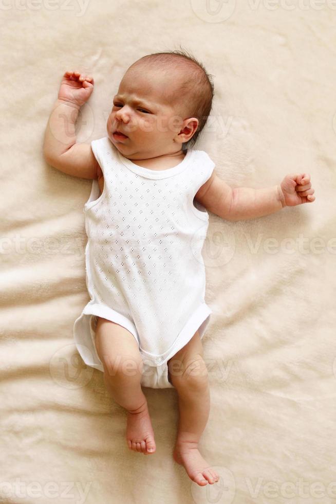Cute newborn child is lying on a blanket and looking into the camera. photo