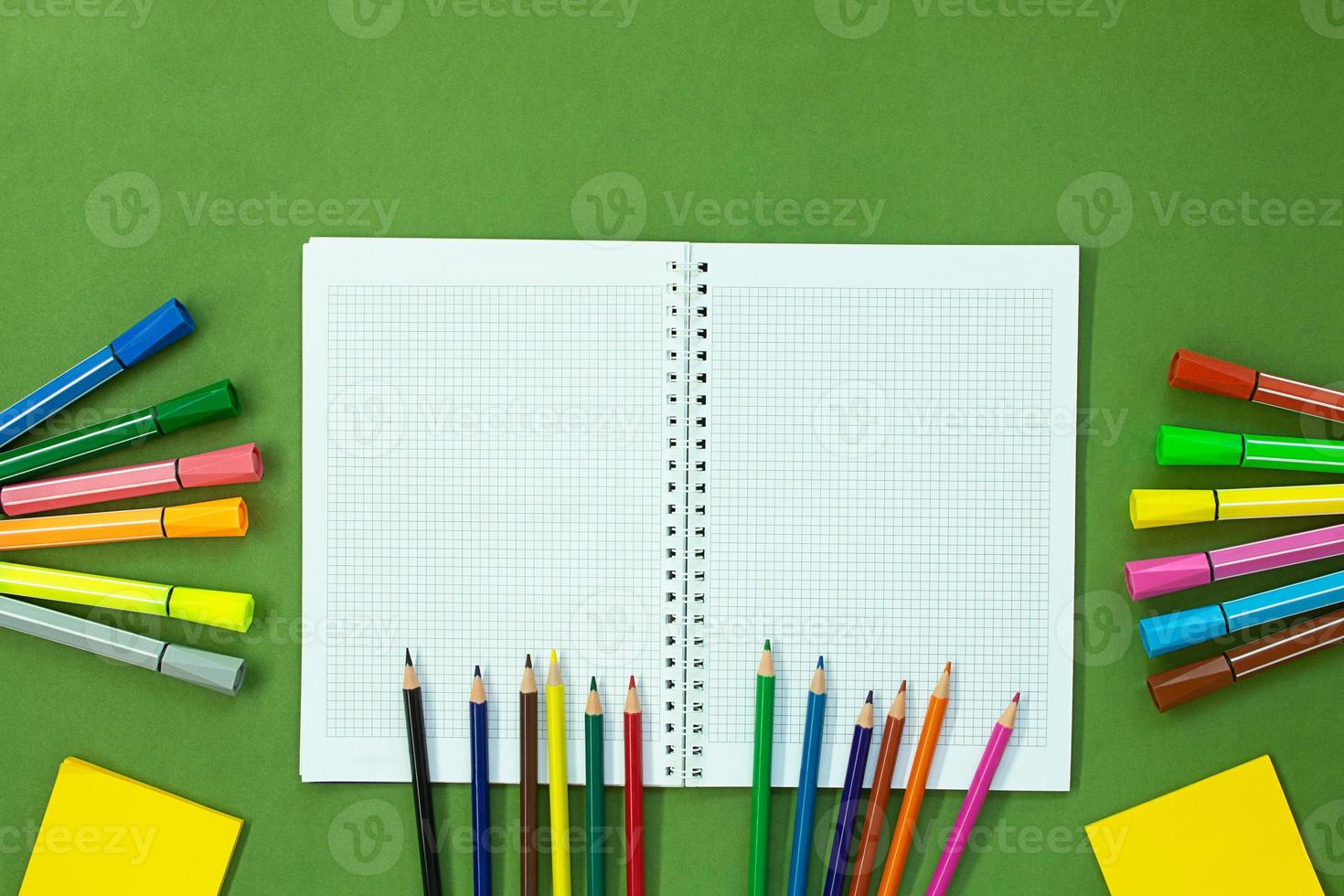 Felt tip pens, colored pencils and note for drawing. Stationery on green background. Concept back to school, education. Copy space photo