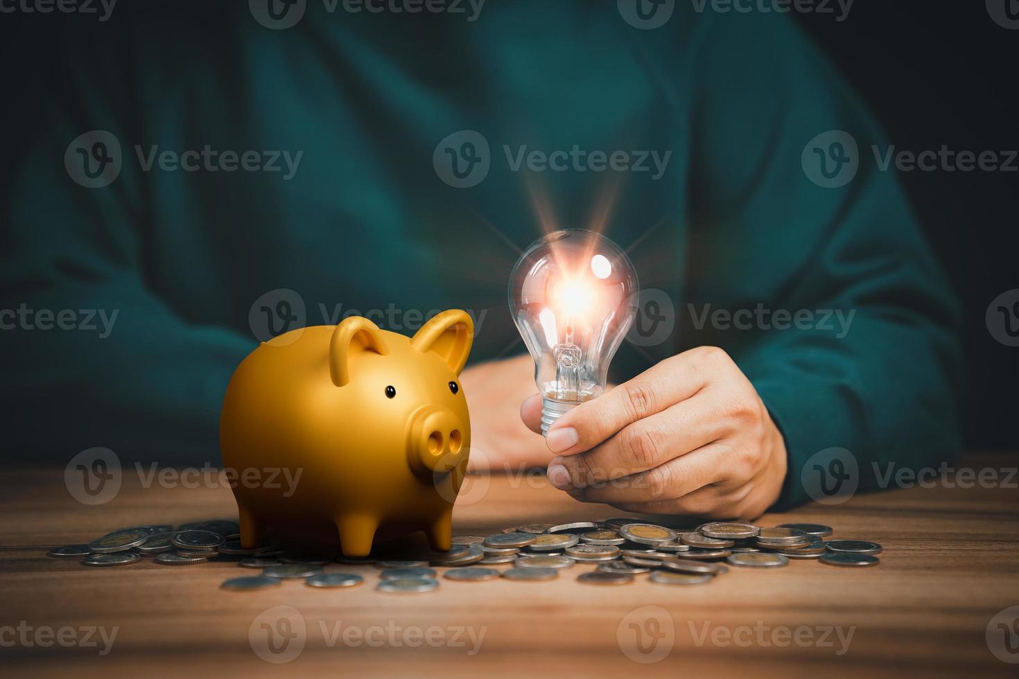Man holding light bulb with coins and piggy bank on desk. Idea saving money, energy and accounting finance in home and family concept. photo