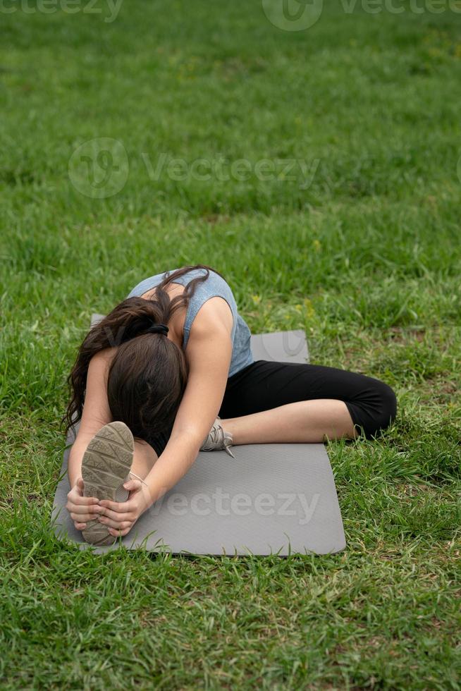 Fitness. Girl sitting on the lawn in the yard of her house, doing excise. photo