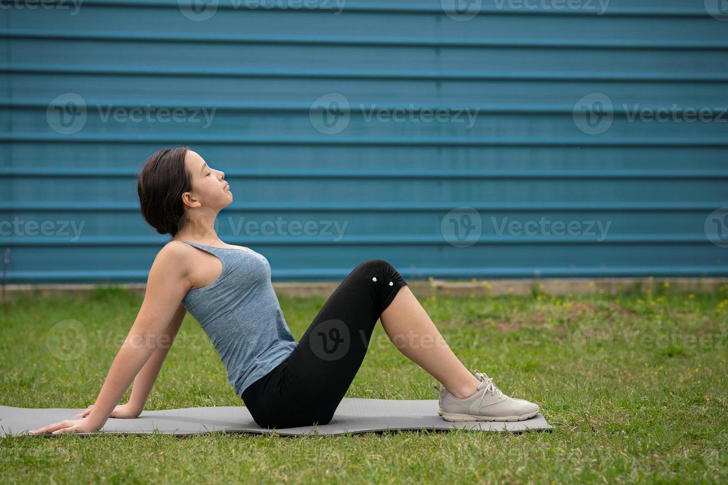 Fitness. Girl sitting on the lawn in the yard of her house, doing excise. photo