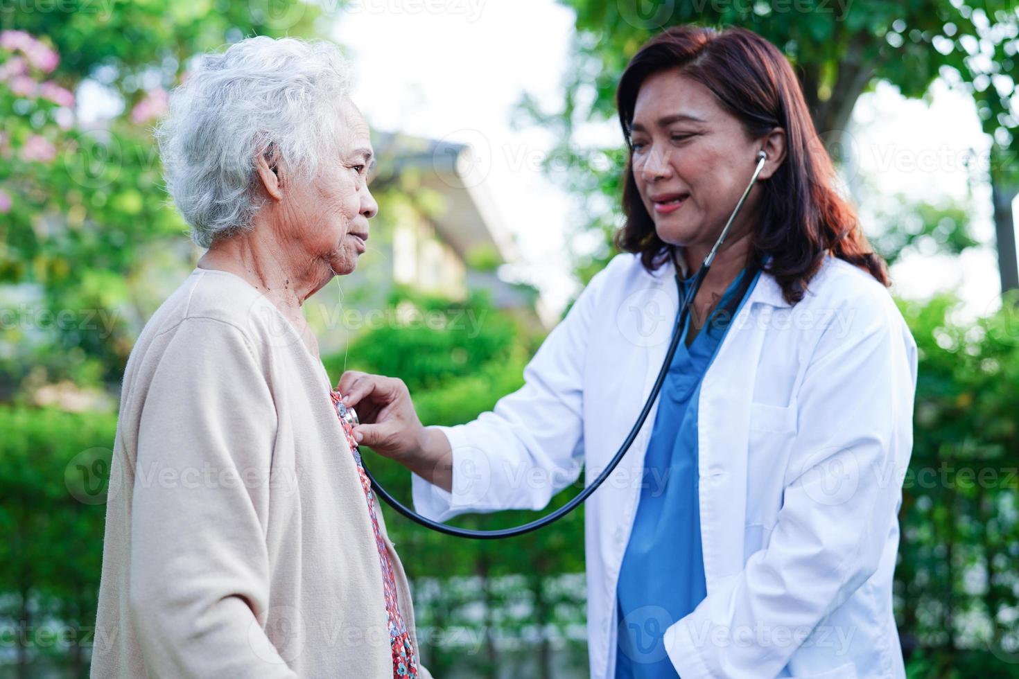 Doctor help Asian elderly woman disability patient walk with walker in park, medical concept. photo