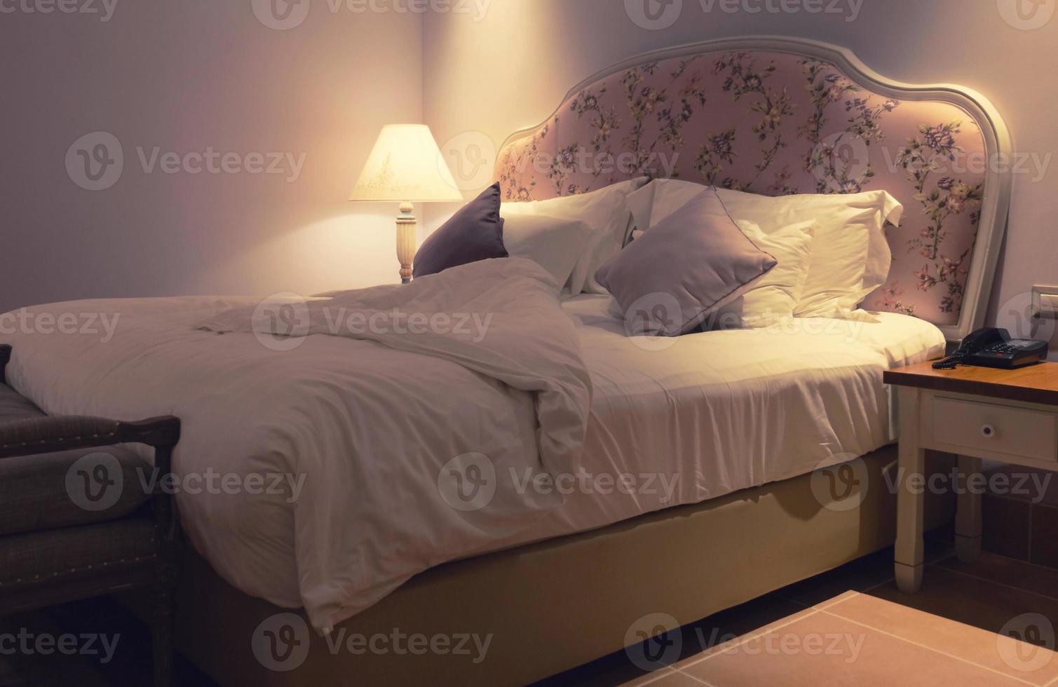untidy bed in hotel at night photo