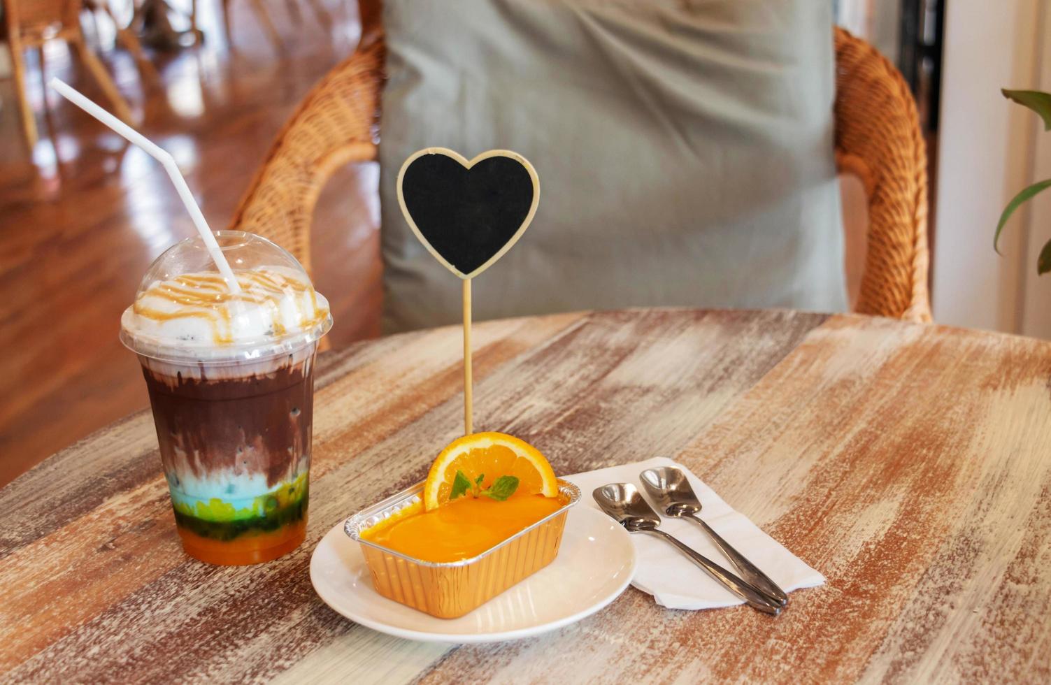 cold mixed cocoa, orange cake and spoons on wooden table photo
