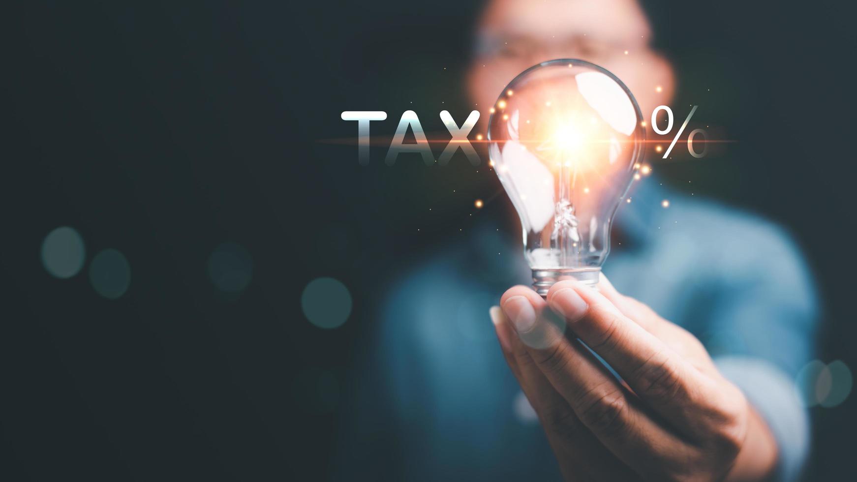 Businessman holding a light bulb ,Effective tax deduction planning ideas for individuals and companies ,Calculating business tax rates and financial budgets , Correct tax rate reduction photo