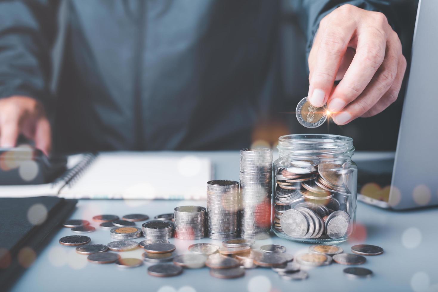 a man shows how to save and save money by putting coins in a glass jar, to invest in finance to make profits grow and generate income through banking and circulating cash through deposit accounts photo