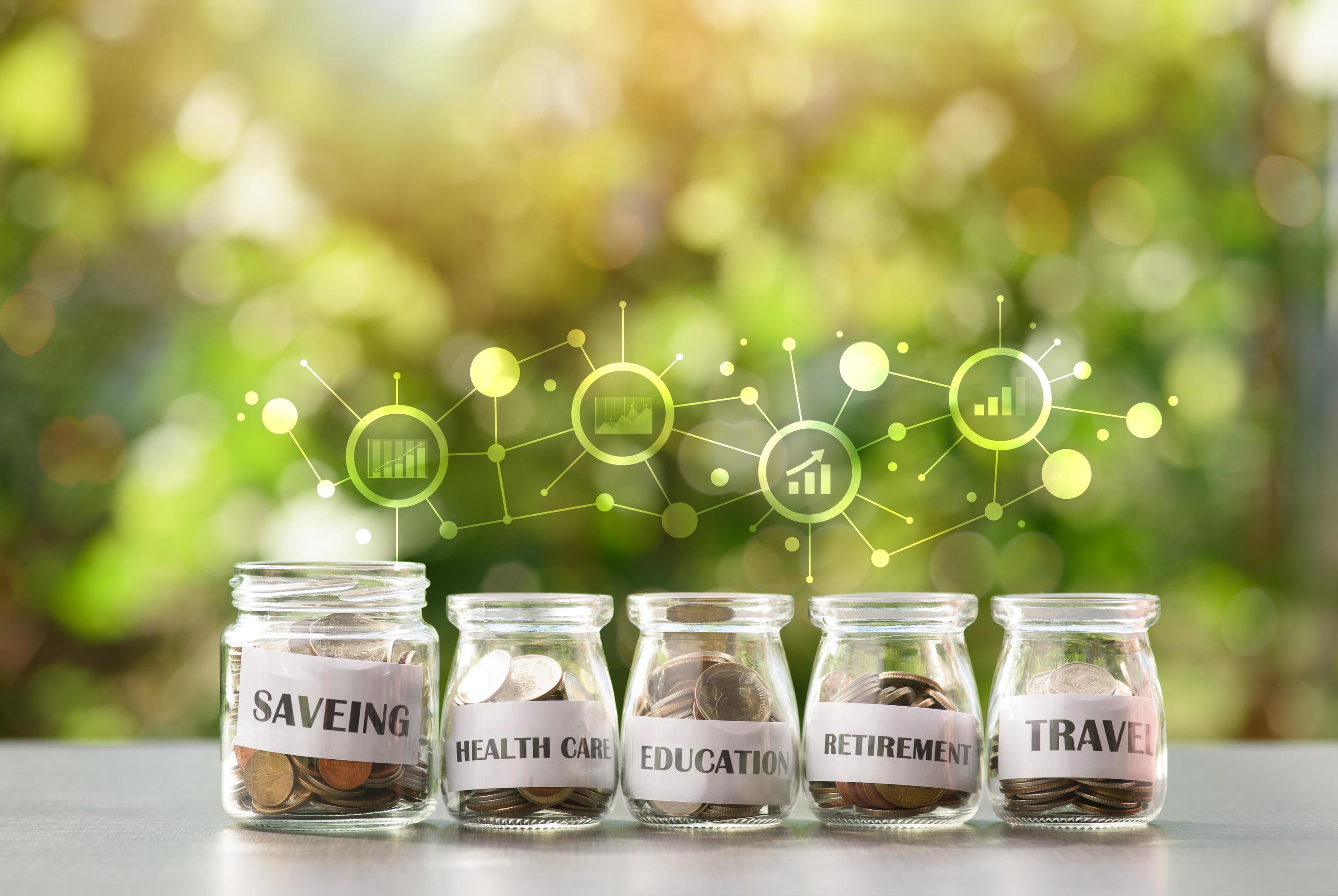 5 glass jars with coins arranged in a natural background, money saving
