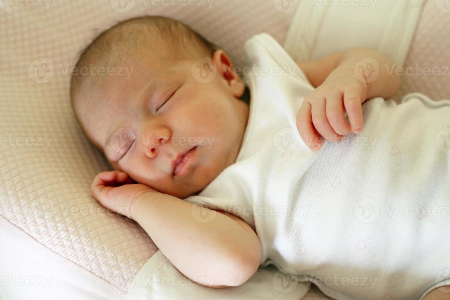 Cute newborn baby is sleeping on her bed. photo