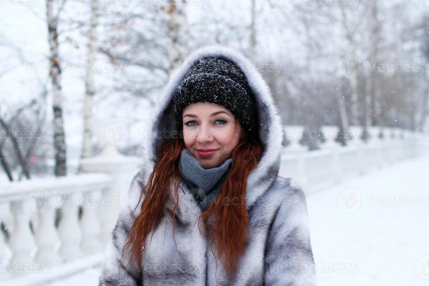 Simular Adaptado preparar joven mujer hermosa con pelo rojo y ojos azules en abrigo de piel sintética  gris con capucha en el fondo del parque nevado de invierno. 13395982 Foto  de stock en Vecteezy