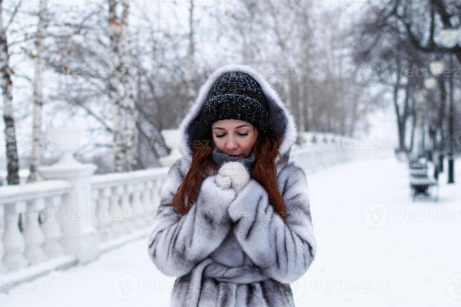 SIDA suelo fumar joven mujer hermosa con pelo rojo en abrigo de piel sintética gris con  capucha en el fondo del parque nevado de invierno. 13395985 Foto de stock  en Vecteezy