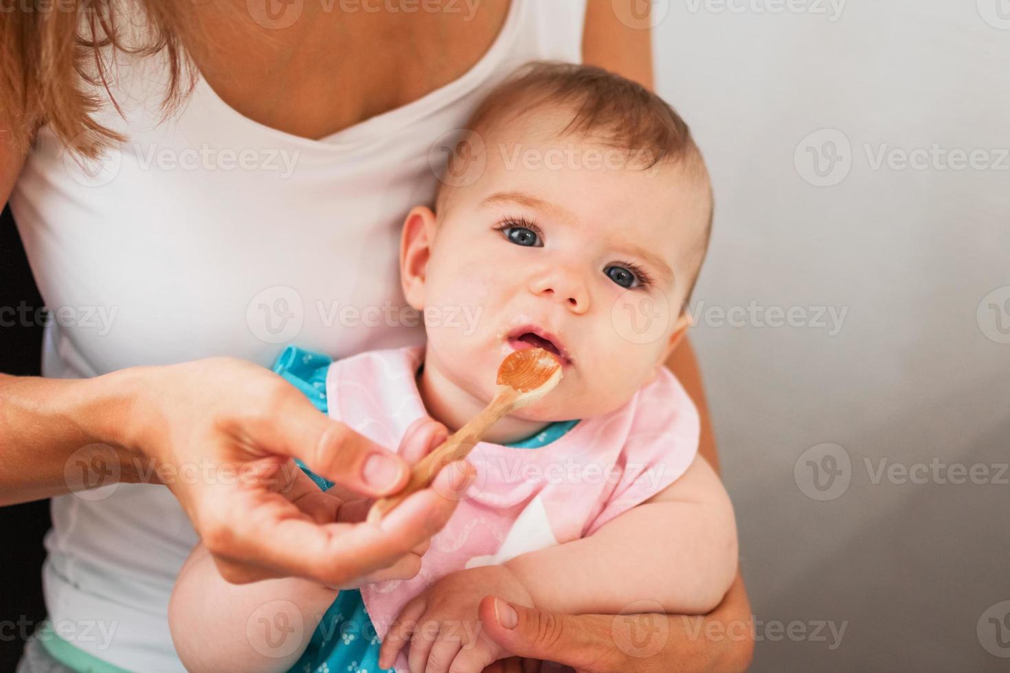 Mother feeding cute baby girl vegetable puree from a spoon. Healthy eating nutrition for little kids photo