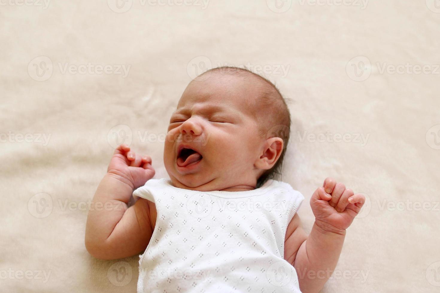 One month child is crying with compressed fists. photo
