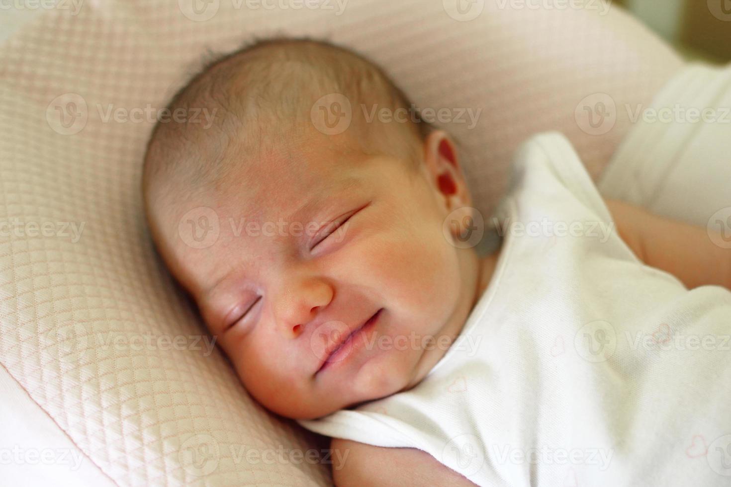 Cute newborn baby is sleeping with smile on her face. photo