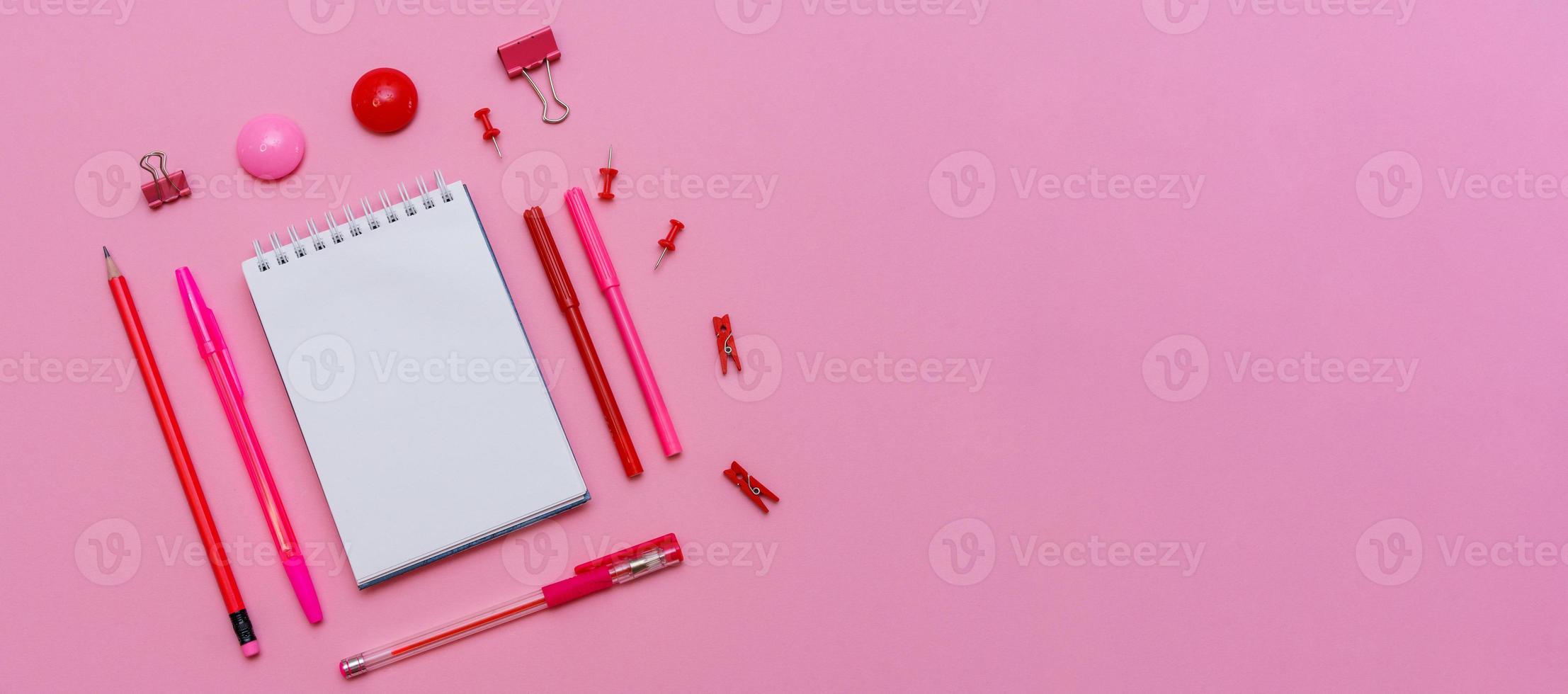 Markers of different pink shades with white notepad on pink background, top photo