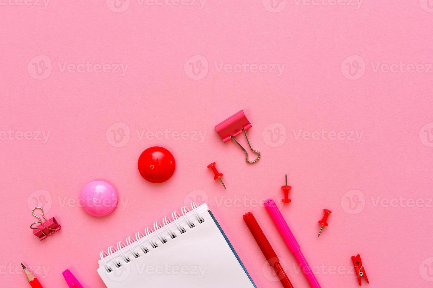 cuaderno blanco se encuentra en forma de blanco sobre fondo rosa con bolígrafo rojo foto