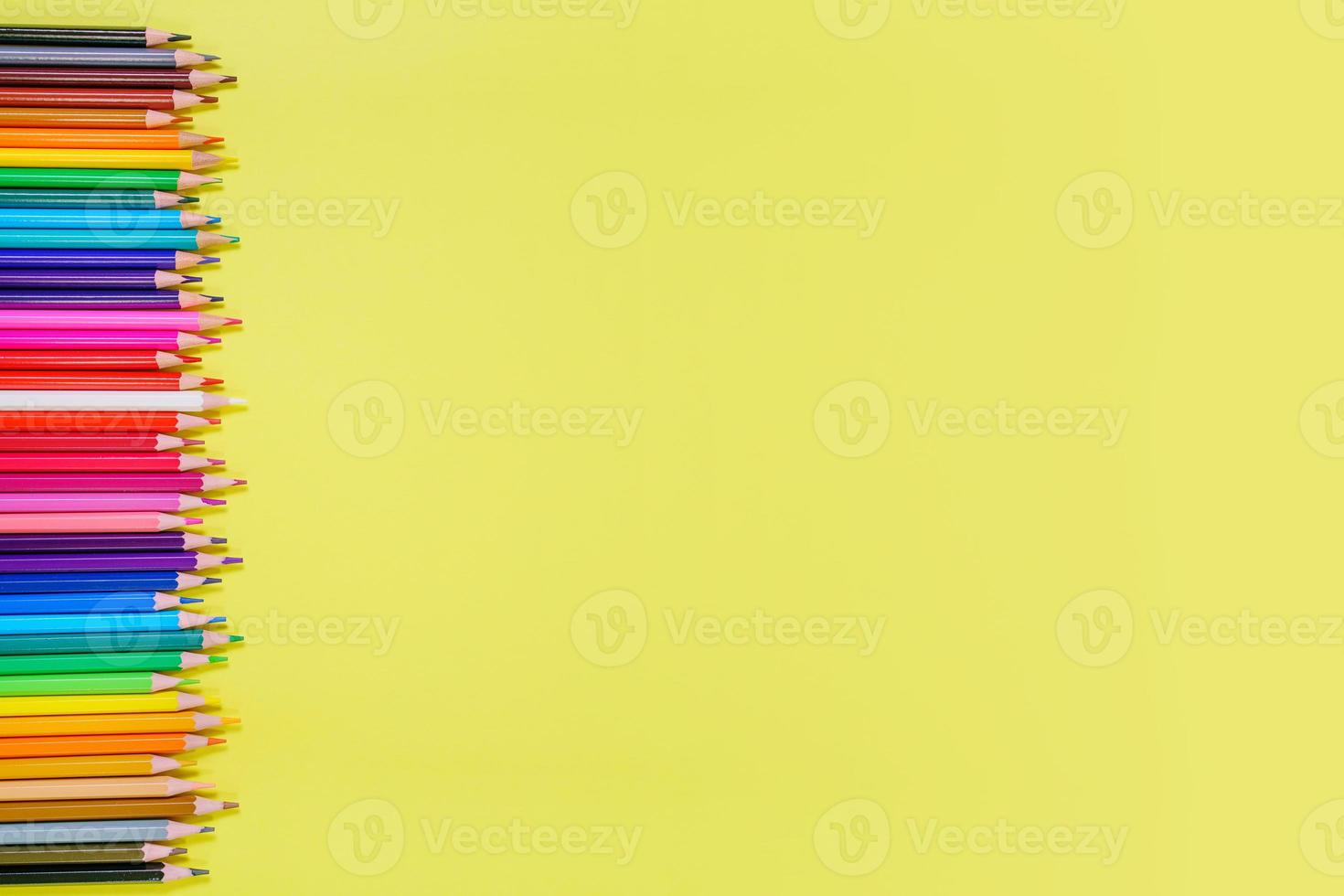 Many different colored pencils on a yellow background. Place your text. photo