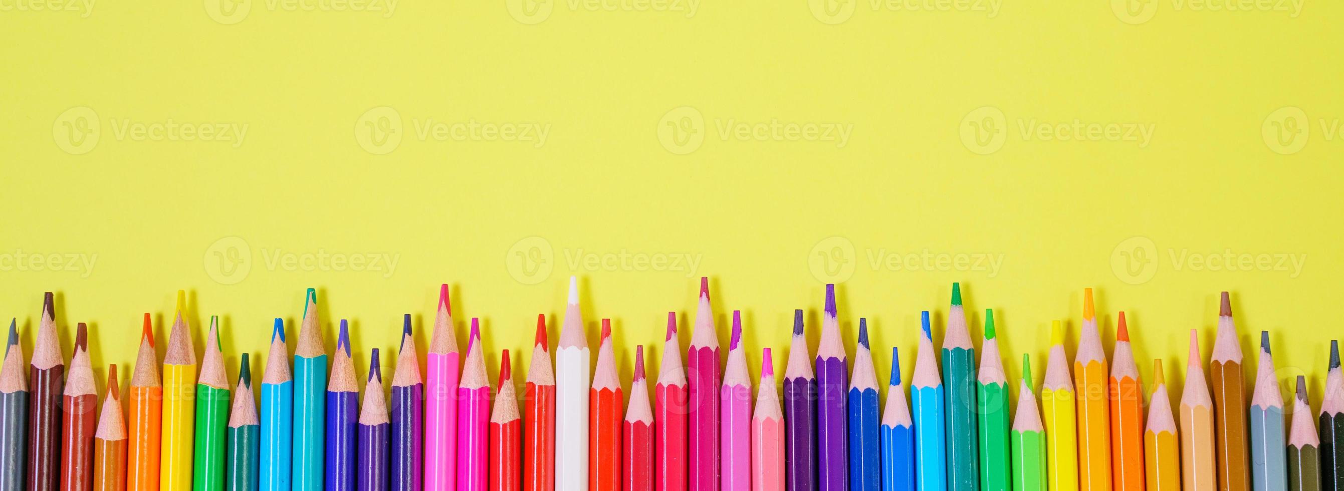 Colored pencils on yellow background top view, back to school concept photo