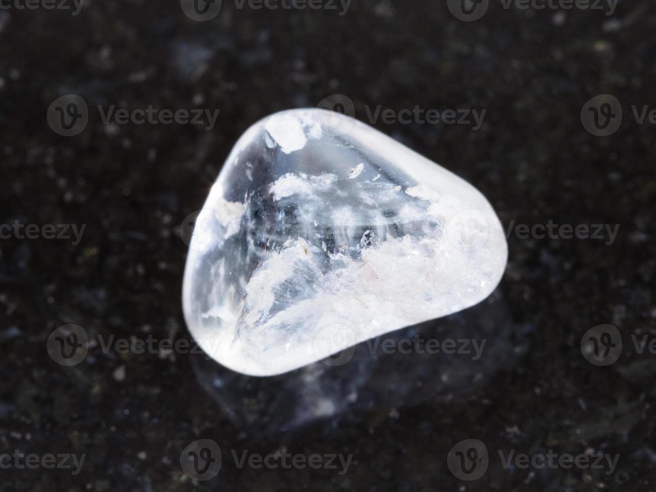 tumbled rock crystal gemstone on dark background photo