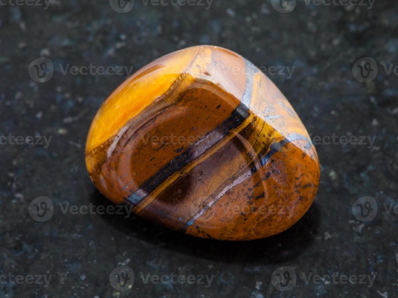 tumbled tigers eye gemstone on dark background photo