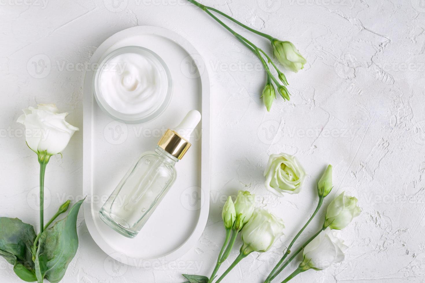 Unbranded bottles in mockup style. Beauty background with facial cosmetic products. Open jar with face cream and dropper bottle with beauty serum on concrete tray. Flat lay photo