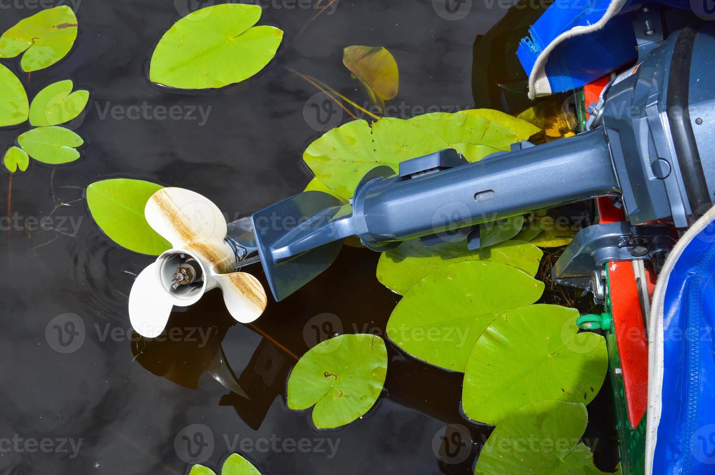 View of the plastic white motor blades of a motorboat of a boat of a swimming vehicle against the background of the water in the river, lake, pond, sea and green lilies photo