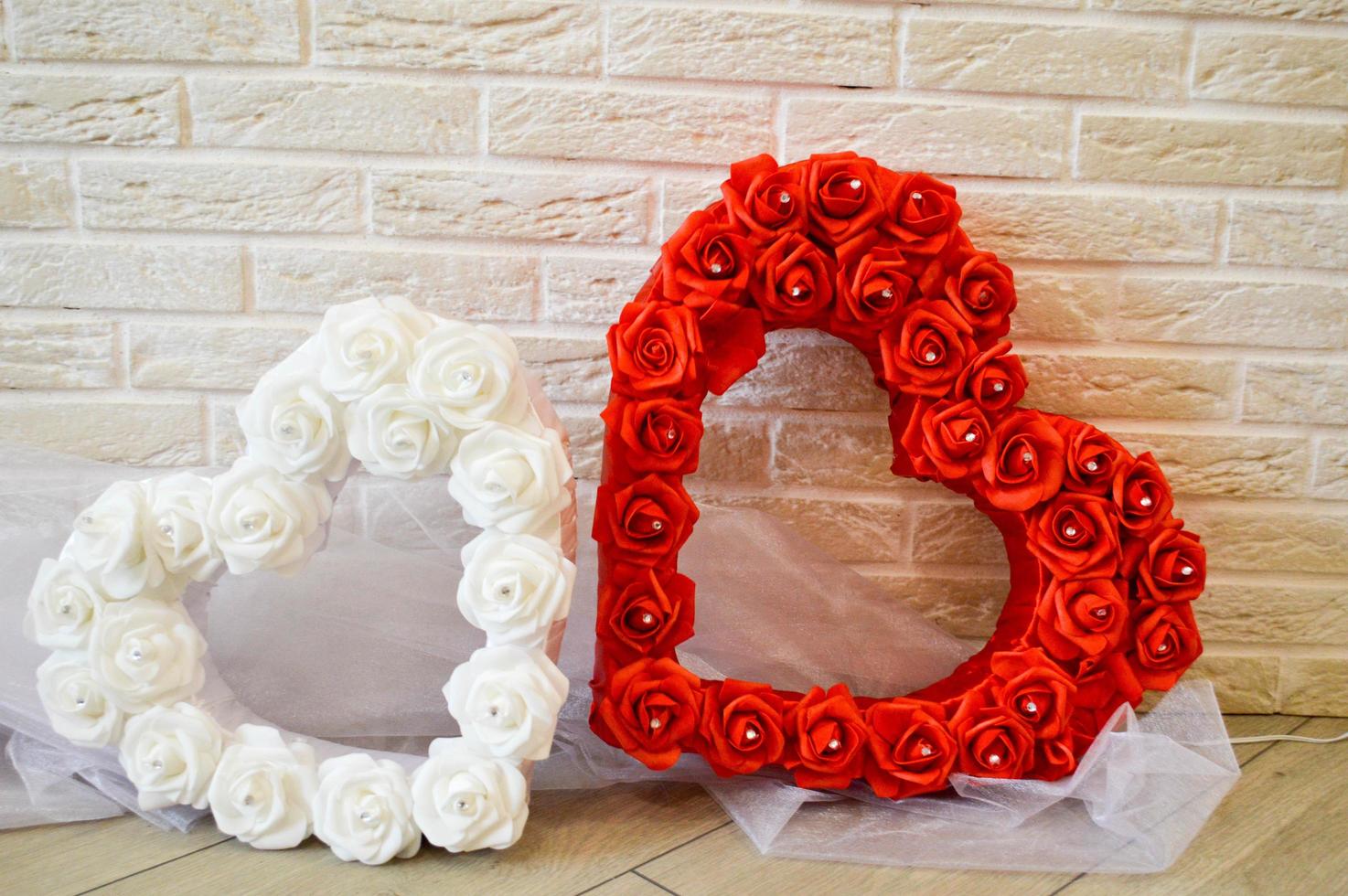 Two hearts. Red and white hearts with a pattern of roses with rhinestones against a brick wall. photo