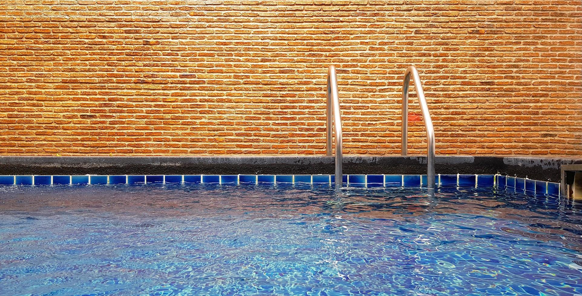 piscina con escalera y fondo de pared de ladrillo con espacio para copiar. interiorismo y estructura. foto