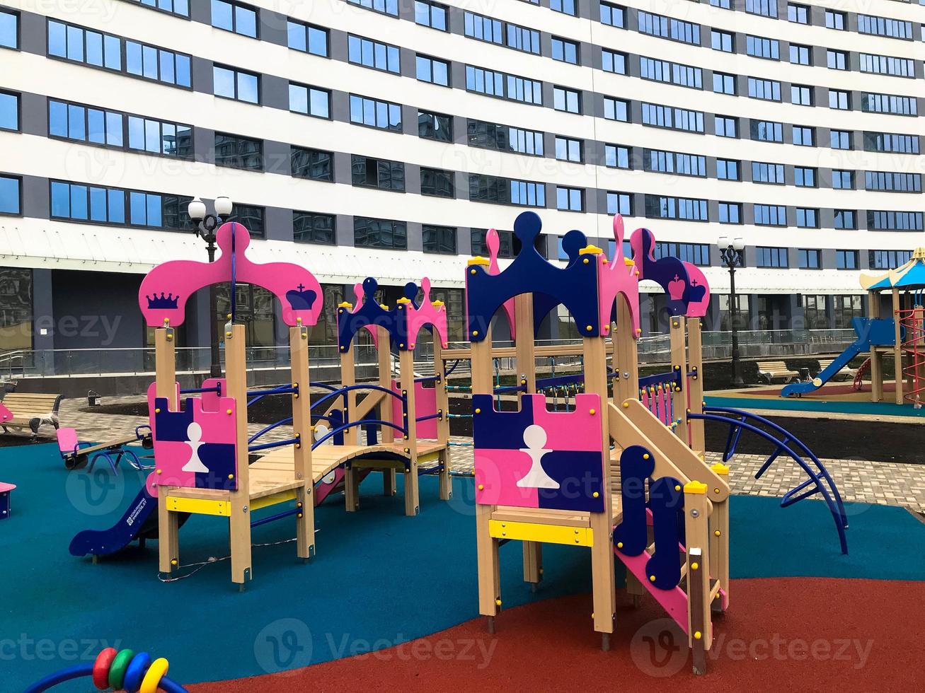 parque infantil rosa en el centro del conjunto residencial. hay columpios, equipos de gimnasia, divertidos toboganes y estructuras para trepar para los niños. patio de recreo en una nueva área al lado de alto foto