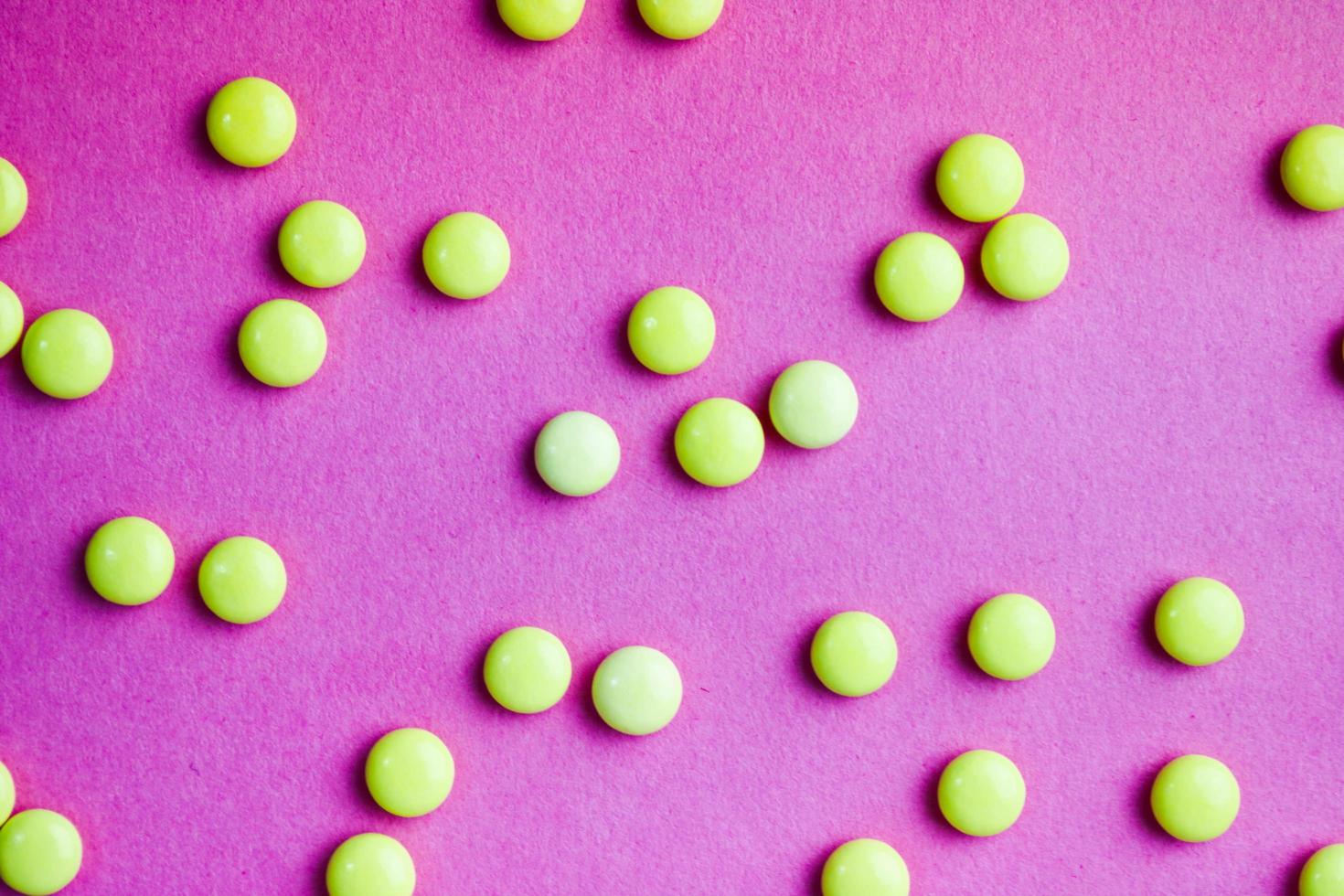 Small yellow orange beautiful medical pharmaceptic round pills, vitamins, drugs, antibiotics on a pink purple background, texture. Concept medicine, health care. Flat lay, top view photo